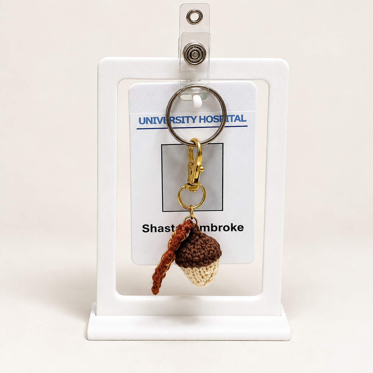 Acorn and oak leaf charm attached in front of an ID badge.